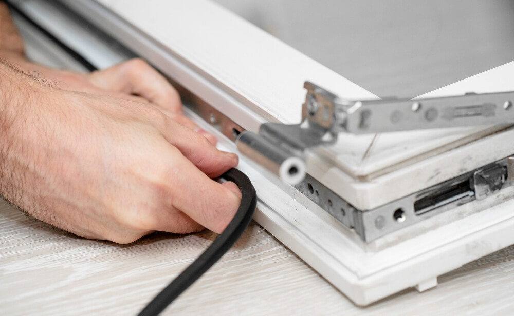 o persoana care instaleaza o garnitura pe un profil de termopan