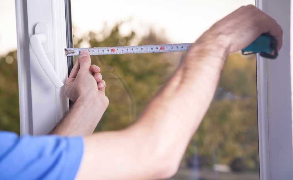 Masuratori termopane o persoana care masoara un geam termopan