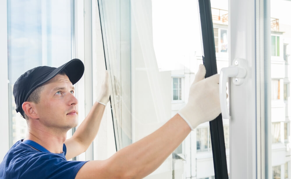 Înlocuire sticlă termopan o persoana care înlocuiește sticla de la o fereastra termopan