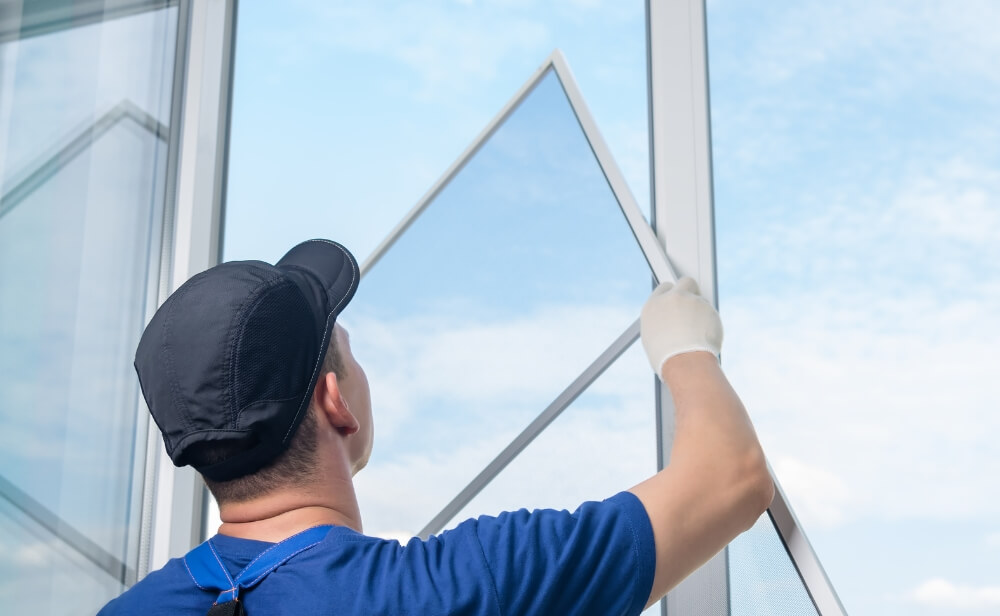 o persoana care monteaza o plasa de insecte pe o fereastra cu termopan