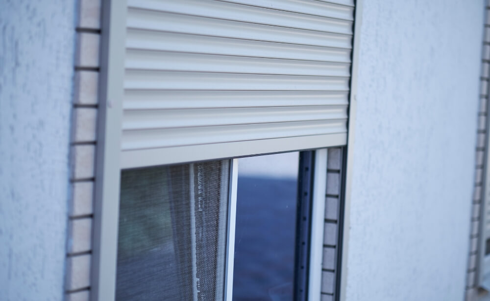 Rulouri exterioare suprapuse o fereastra vazuta din exterior cu rulouri exterioare trase pana la jumatatea geamului