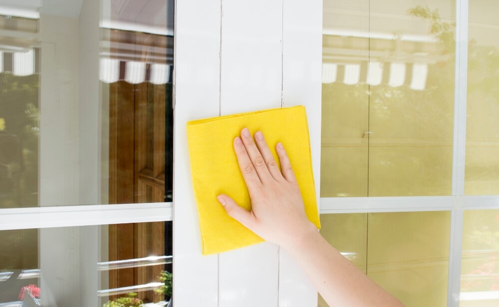 Întreținere tâmplărie aluminiu o femeie care șterge o fereastră de aluminiu cu o cârpă